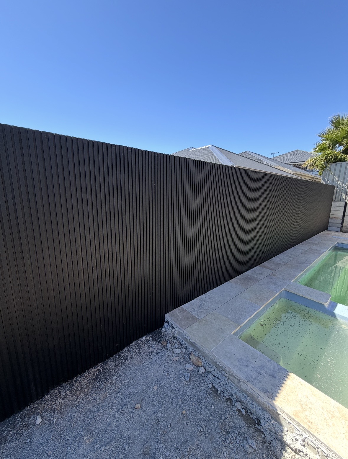 Black aluminium slat fence beside a backyard pool